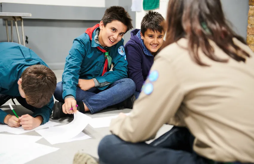 a young leader supporting three scouts to come up with programme ideas