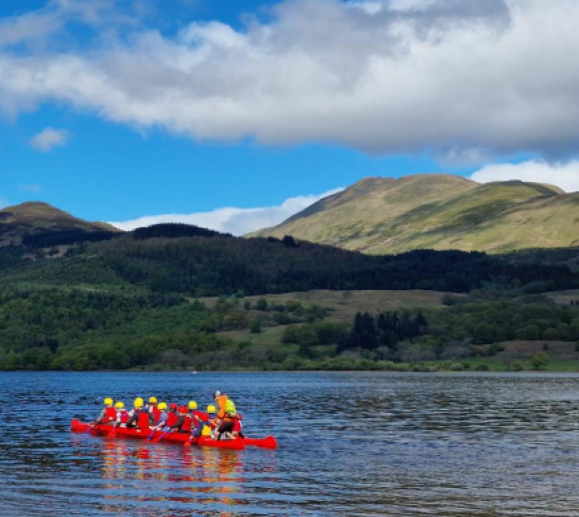 scouts in a canoe on a loch with a hill in the background